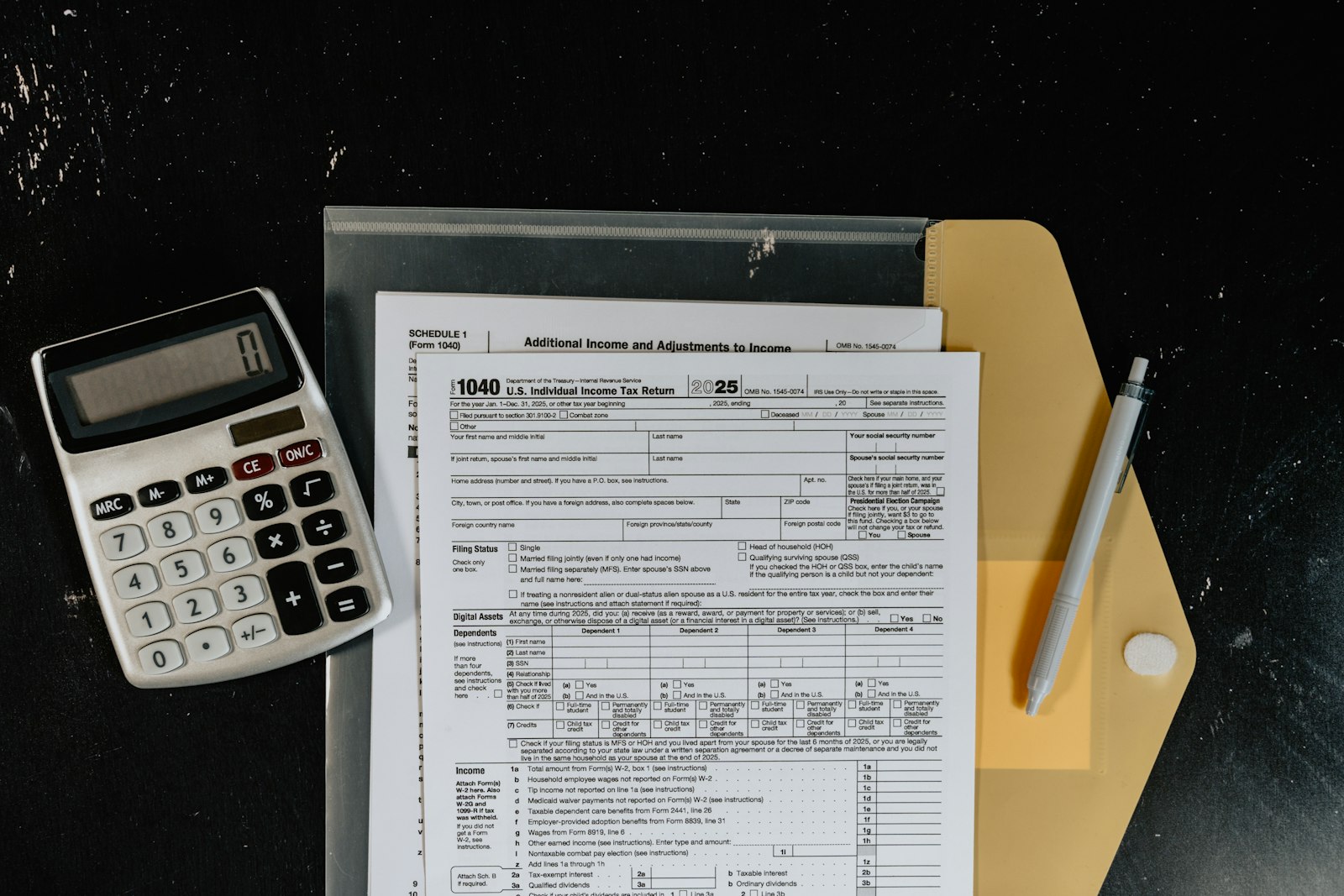 Calculator, tax return form, and folder on a desk